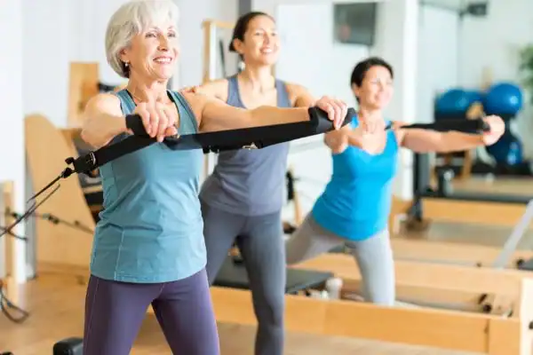 Toning Arms After 60: Empowering Womens Fitness Through Effective Weight Training 2 older woman doing weight training Edgware and resistance in the gym to tone upper arms